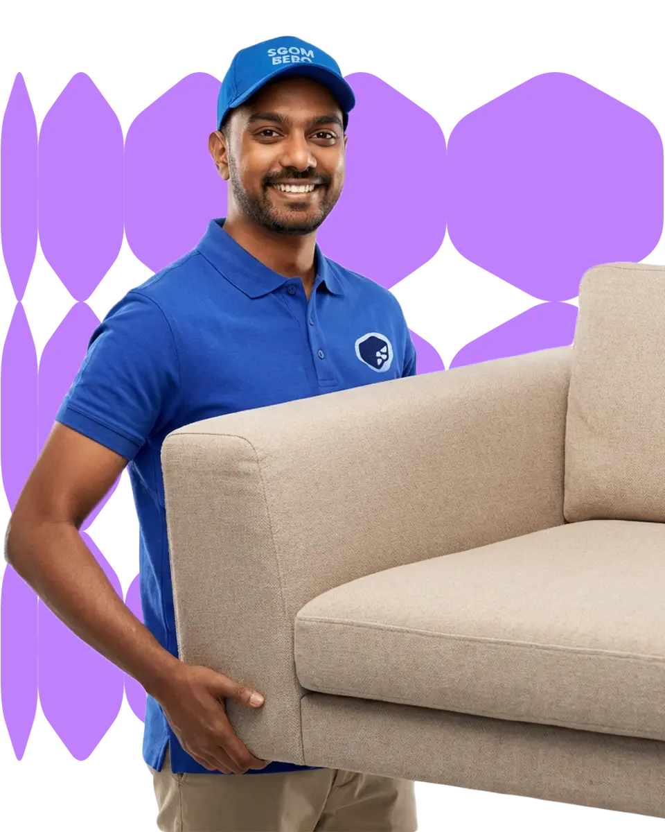 Operatore professionale in uniforme blu che trasporta un divano beige durante uno sgombero Operatore professionale in uniforme blu che trasporta un divano beige durante uno sgombero